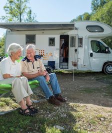 Grey nomad couple sitting outside campervan