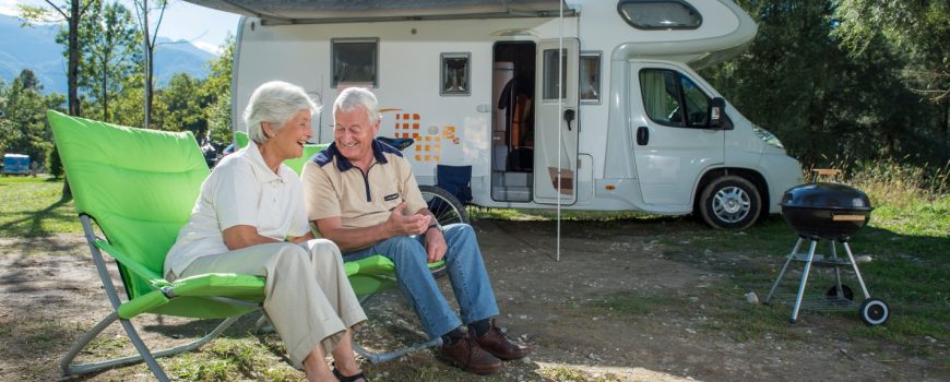 Grey nomad couple sitting outside campervan - install photoelectric smoke alarms today for safety
